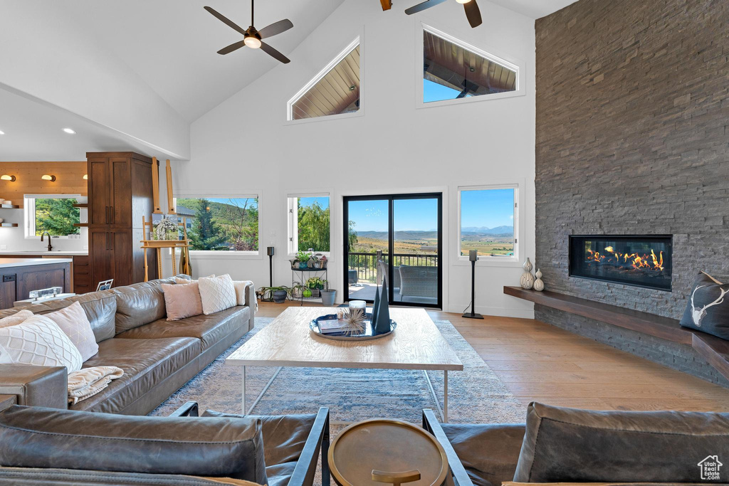 Living room with plenty of natural light, ceiling fan, and a stone fireplace