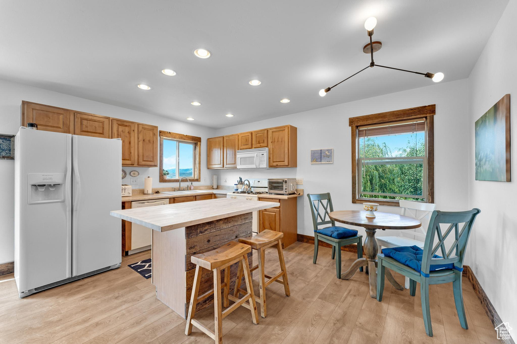 Kitchen featuring white appliances, plenty of natural light, light hardwood / wood-style floors, and sink