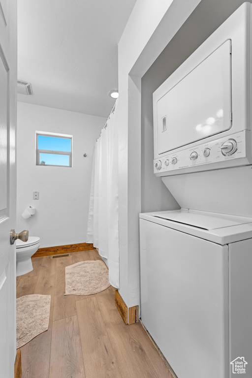 Laundry room featuring light hardwood / wood-style flooring and stacked washer / drying machine