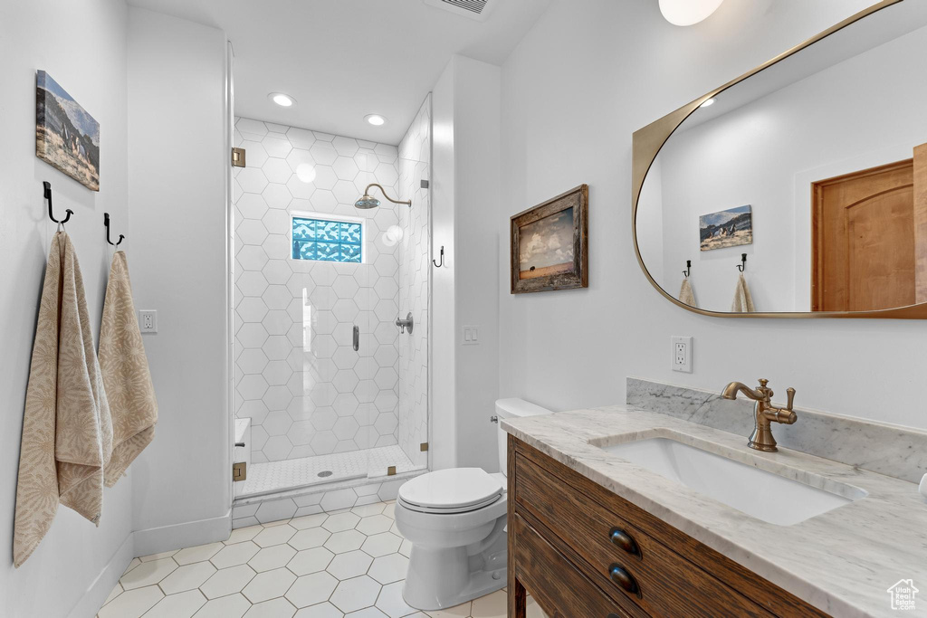 Bathroom featuring vanity, toilet, an enclosed shower, and tile patterned floors