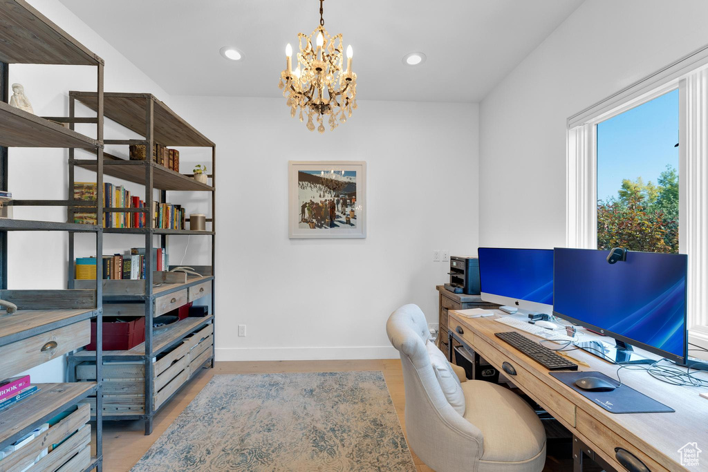 Home office featuring light wood-type flooring and a notable chandelier