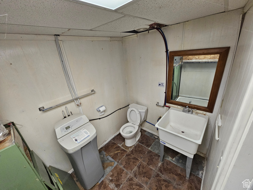 Bathroom featuring toilet, sink, and a drop ceiling