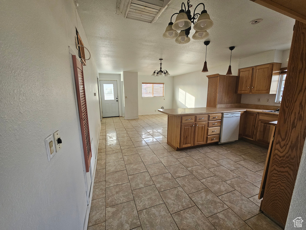 Kitchen with dishwasher, hanging light fixtures, a notable chandelier, kitchen peninsula, and light tile patterned floors