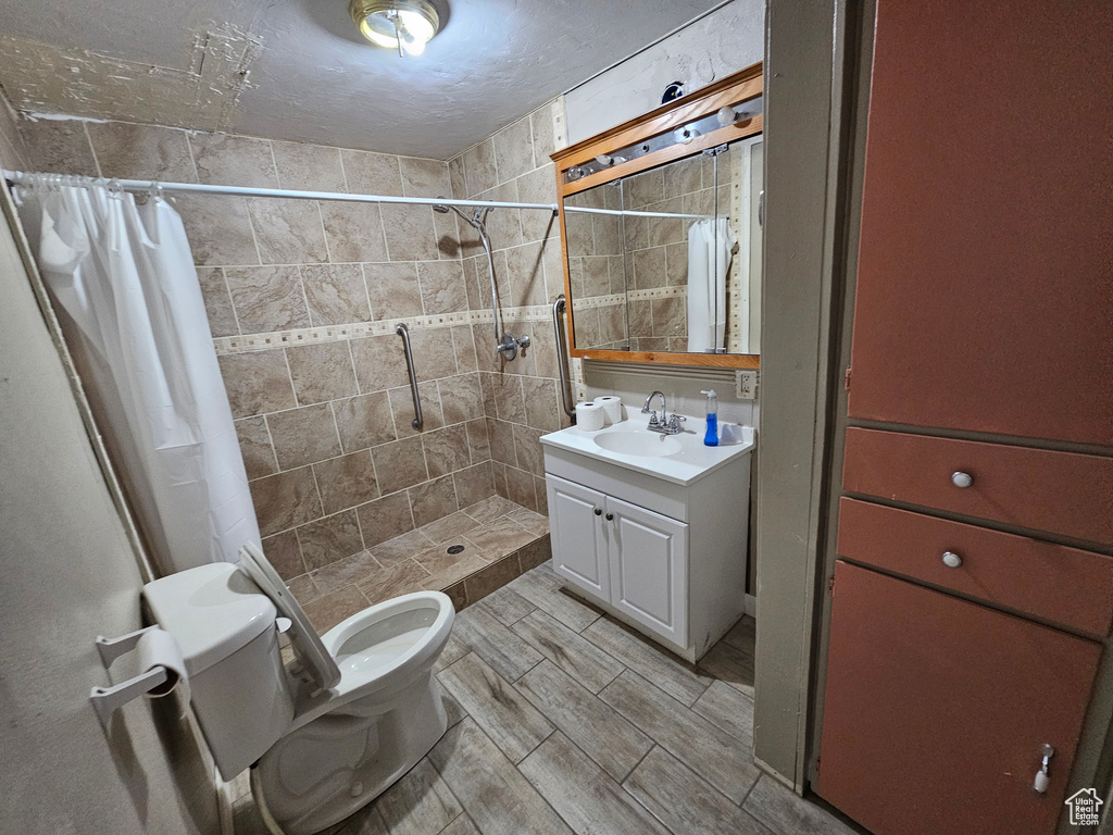 Bathroom with a textured ceiling, vanity, toilet, and a shower with curtain