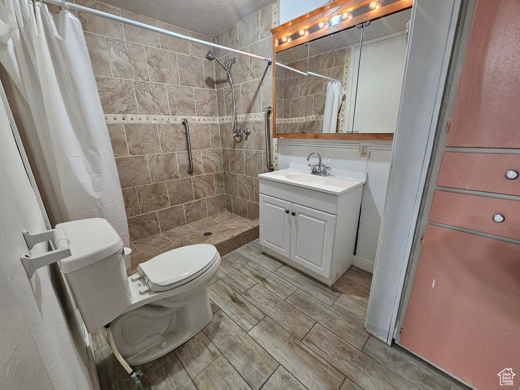 Bathroom featuring vanity, curtained shower, and toilet