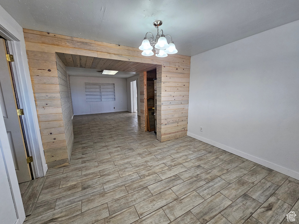 Unfurnished dining area with wood walls and an inviting chandelier