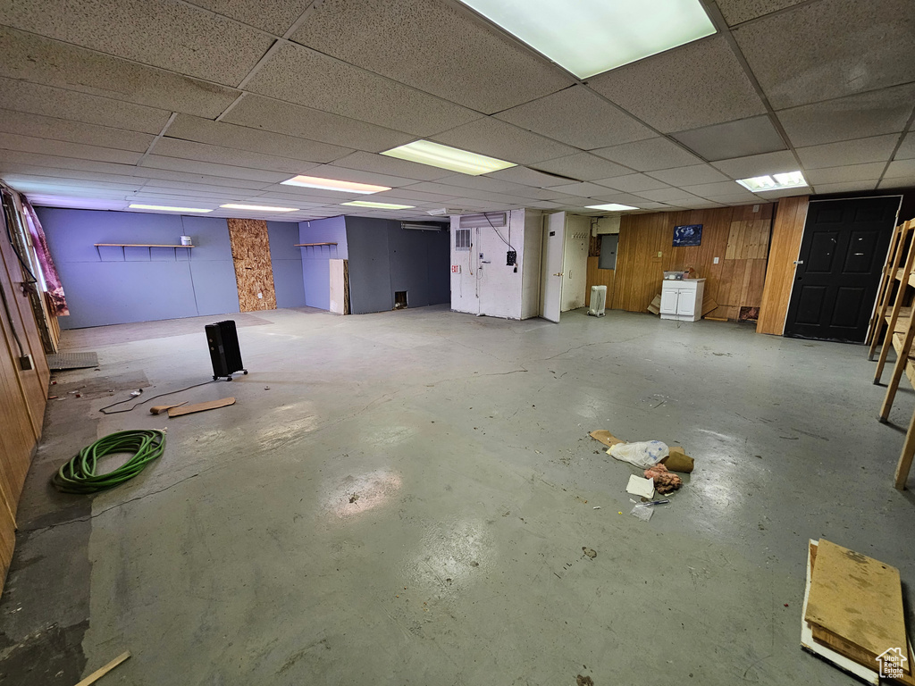 Basement with a paneled ceiling, washer / dryer, and wood walls