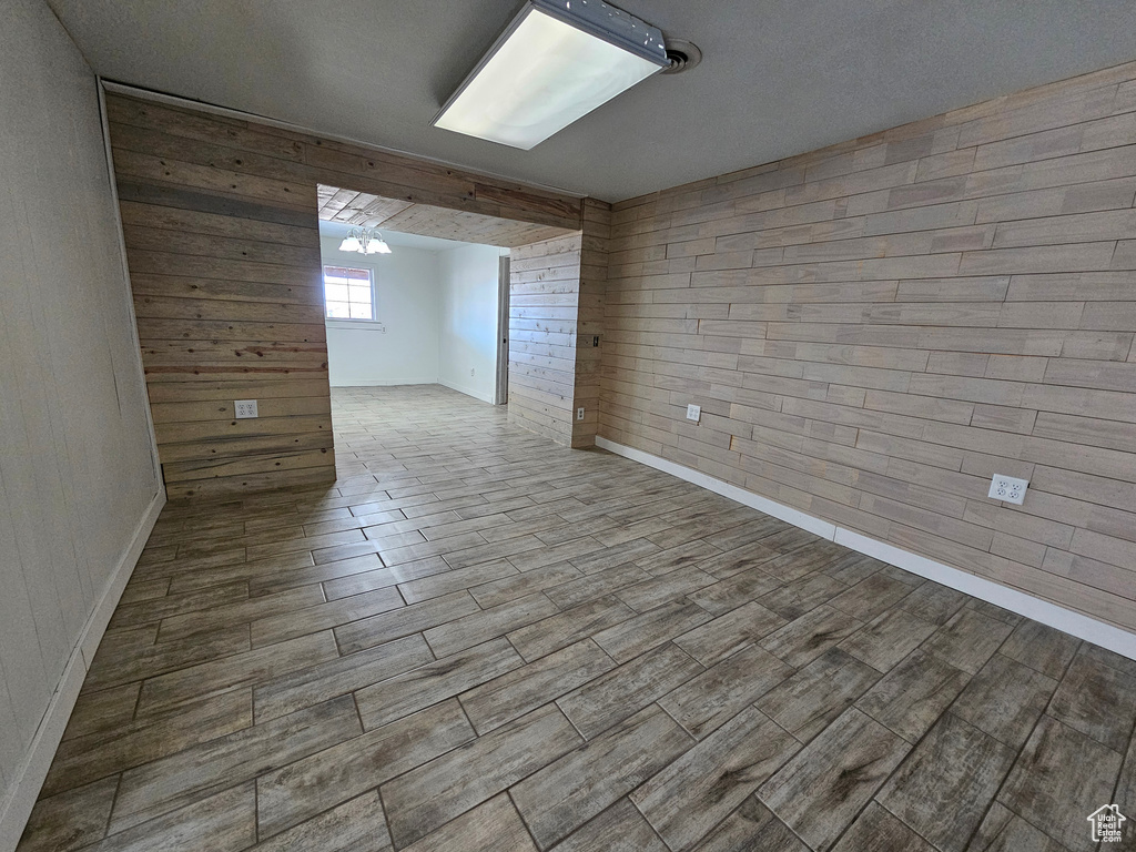 Empty room with a chandelier, a textured ceiling, and wood walls