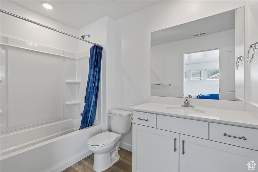 Full bathroom with toilet, hardwood / wood-style flooring, shower / tub combo, and vanity