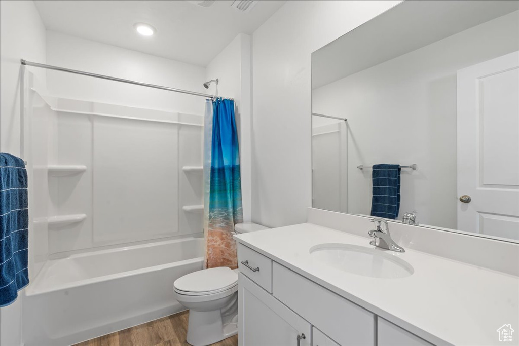 Full bathroom with shower / bath combination with curtain, toilet, hardwood / wood-style flooring, and vanity