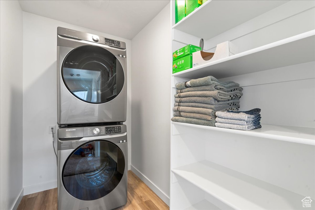 Laundry area featuring hardwood / wood-style floors and stacked washer / drying machine