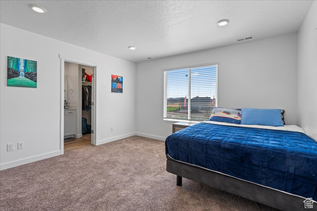 Carpeted bedroom featuring a walk in closet, a closet, and a textured ceiling