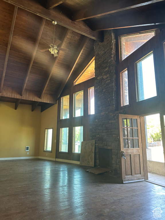 Unfurnished living room featuring wood-type flooring, a stone fireplace, and high vaulted ceiling