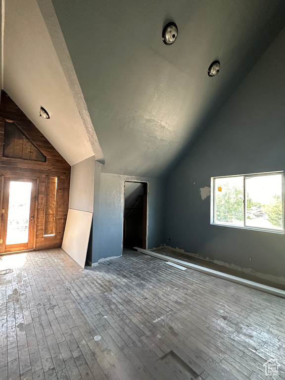 Bonus room featuring wood-type flooring, wooden walls, and a textured ceiling