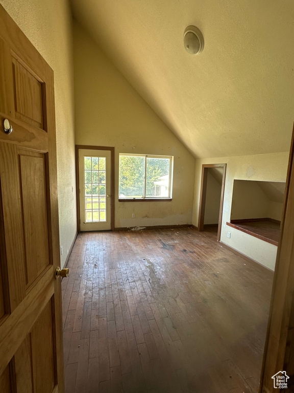 Bonus room featuring lofted ceiling, hardwood / wood-style flooring, and a textured ceiling