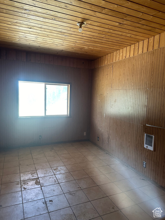 Tiled spare room with wood ceiling, wood walls, and heating unit