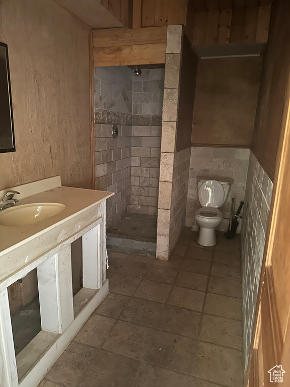 Bathroom featuring vanity, toilet, and a tile shower