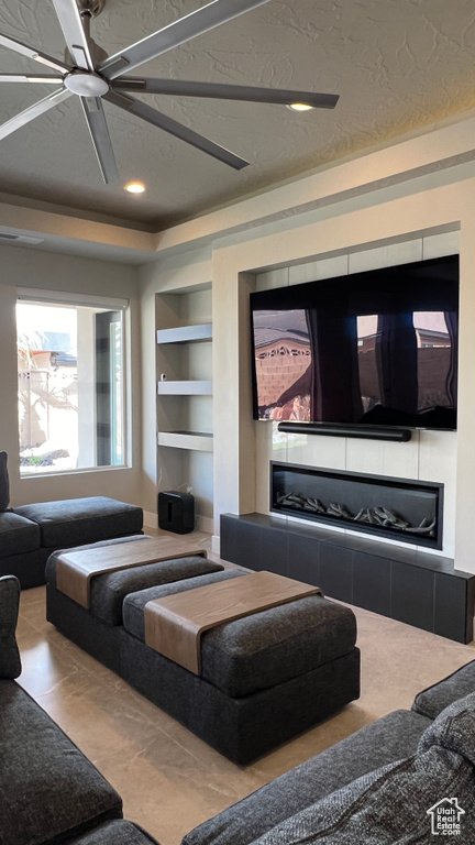 Living room with built in features, ceiling fan, and a textured ceiling