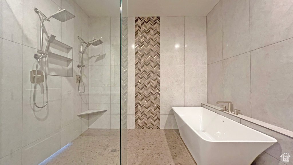 Bathroom featuring tile walls and shower with separate bathtub