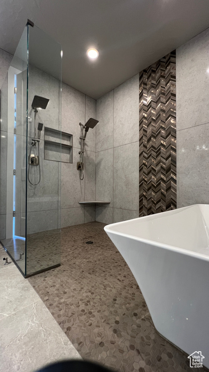 Bathroom featuring tile walls and shower with separate bathtub