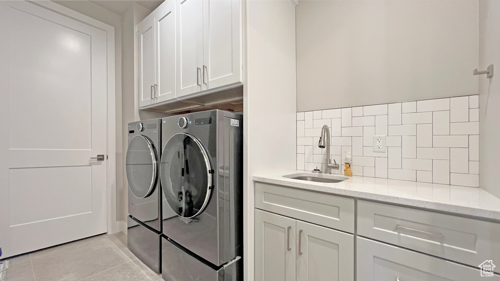 Washroom with washing machine and dryer, cabinets, sink, and light tile patterned flooring