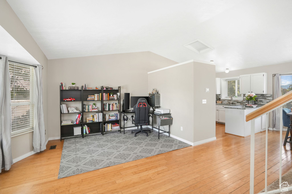 Office space with light wood-type flooring and vaulted ceiling