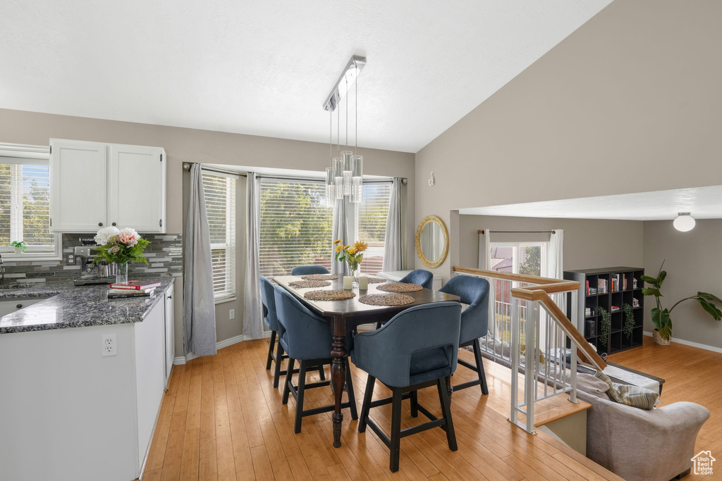 Dining area featuring light wood-type flooring, vaulted ceiling, sink, and a healthy amount of sunlight