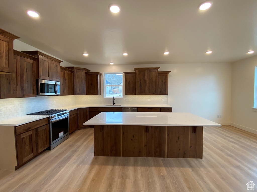 Kitchen with a center island, light hardwood / wood-style flooring, stainless steel appliances, and sink