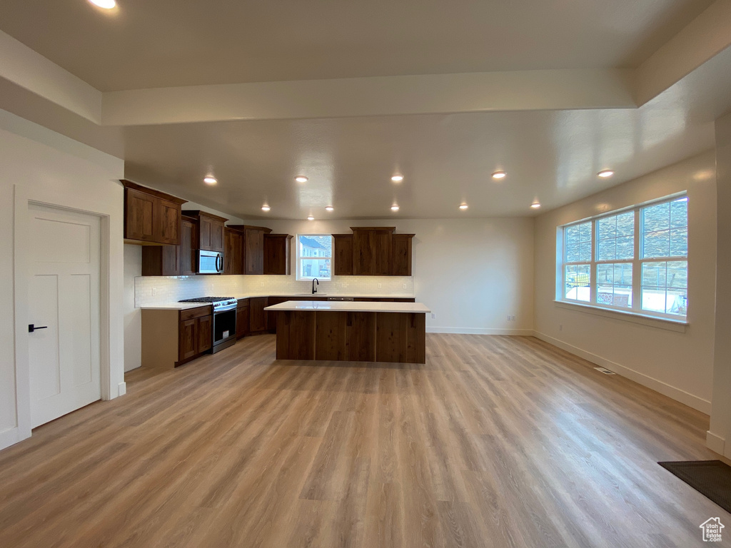 Kitchen with a kitchen island, stainless steel appliances, sink, and light hardwood / wood-style flooring