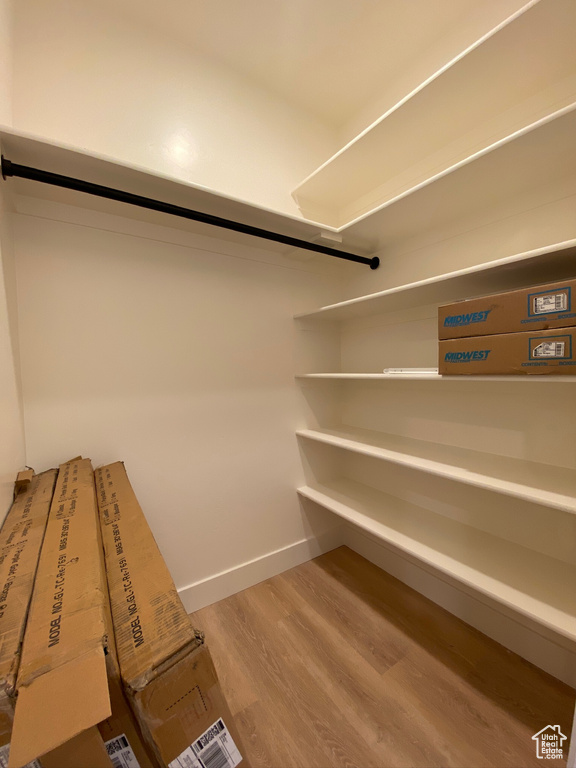 Walk in closet with hardwood / wood-style floors