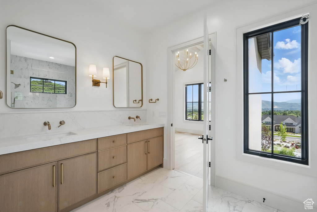 Bathroom featuring marble look tiles, a mountain view, double vanity, and plenty of natural light