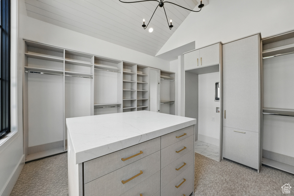 Spacious closet featuring a chandelier, light carpet, and high vaulted ceiling