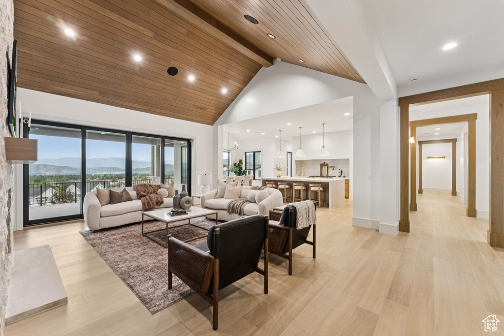 Living area with high vaulted ceiling, beam ceiling, a mountain view, light wood-style flooring, and recessed lighting