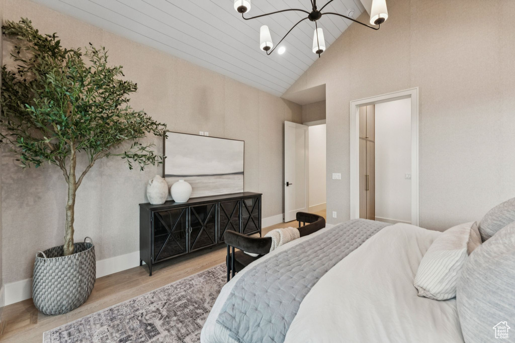 Bedroom featuring a chandelier, wood finished floors, and high vaulted ceiling