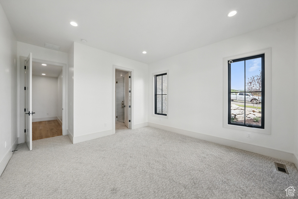 Unfurnished bedroom featuring light carpet, recessed lighting, baseboards, and ensuite bathroom