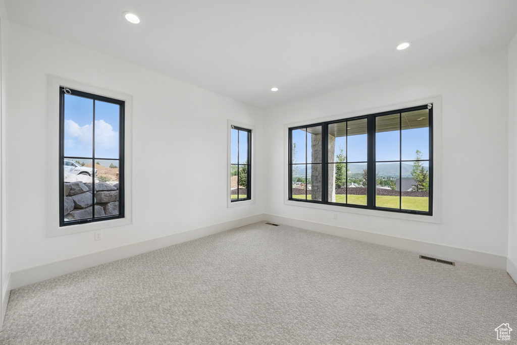 Spare room featuring healthy amount of natural light, recessed lighting, and carpet
