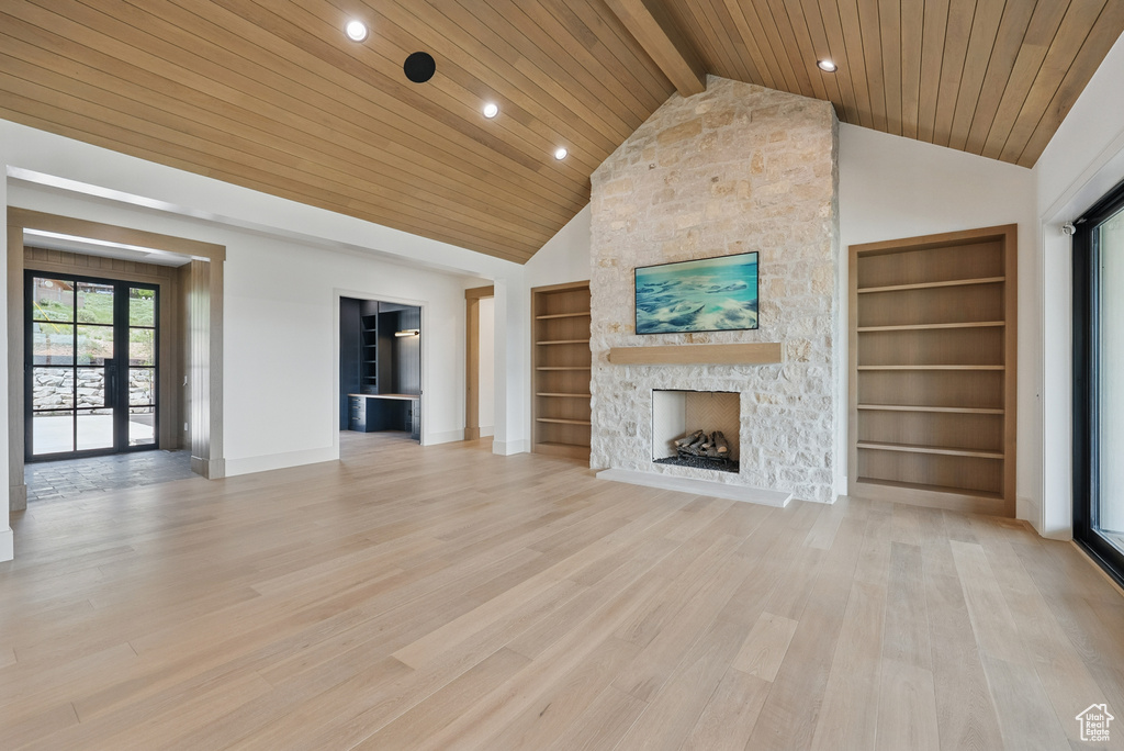 Unfurnished living room featuring a fireplace, wood ceiling with exposed beams, built in features, light wood finished floors, and baseboards