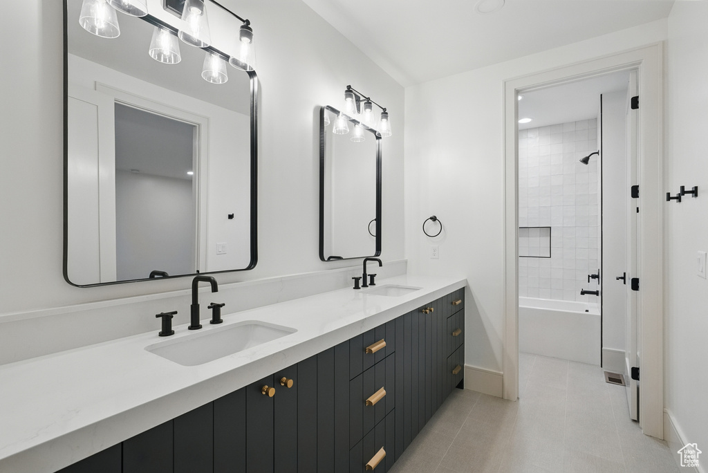 Bathroom featuring double vanity, baseboards, tub / shower combination, and tile patterned flooring