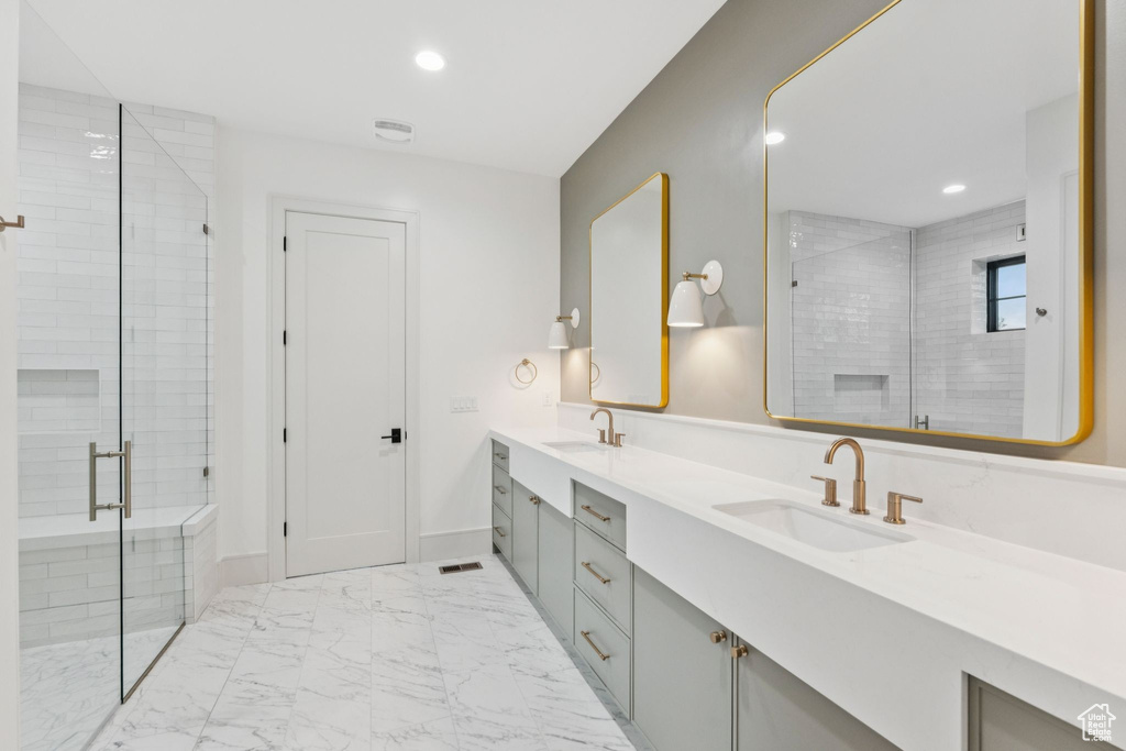 Full bath with double vanity, a shower stall, marble finish flooring, and recessed lighting