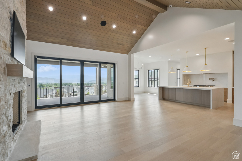 Unfurnished living room featuring high vaulted ceiling, a fireplace, light wood-type flooring, recessed lighting, and wood ceiling with exposed beams