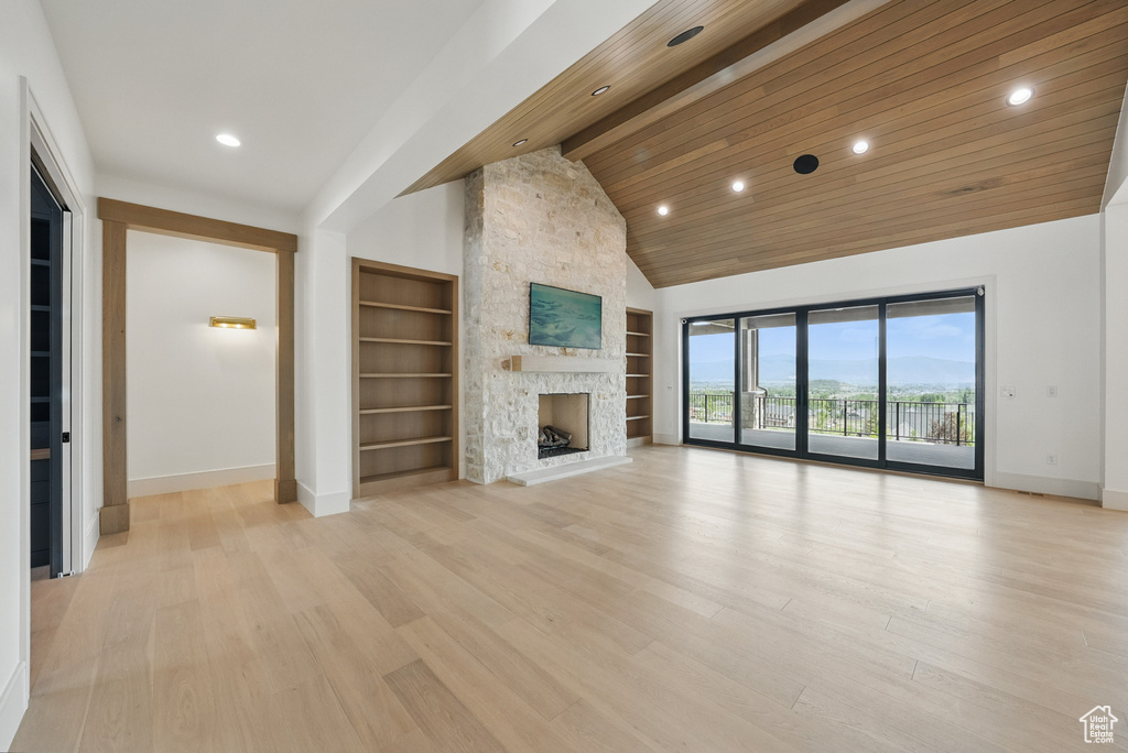 Unfurnished living room with baseboards, built in features, a stone fireplace, light wood-style floors, and recessed lighting