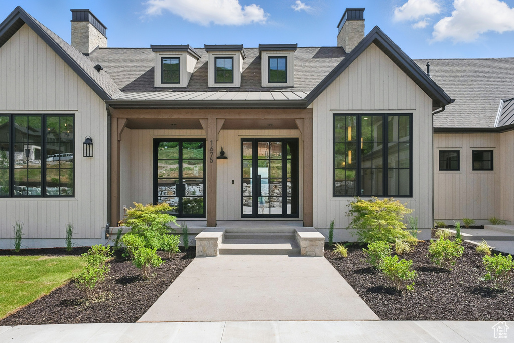 Doorway to property with a chimney and a shingled roof