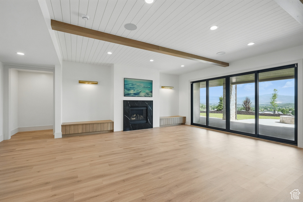Unfurnished living room with recessed lighting, beam ceiling, light wood-style flooring, a fireplace, and baseboards