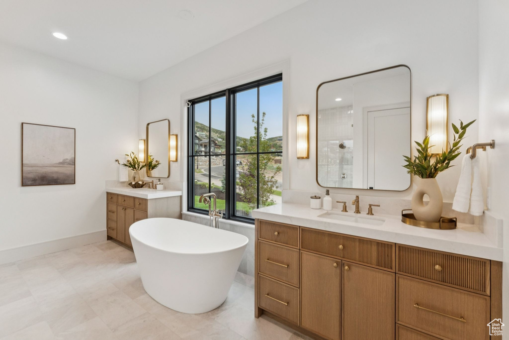Full bathroom with two vanities, a freestanding tub, a tile shower, and recessed lighting