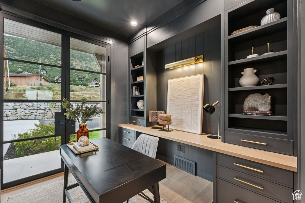 Home office with wood finished floors, built in shelves, and built in desk