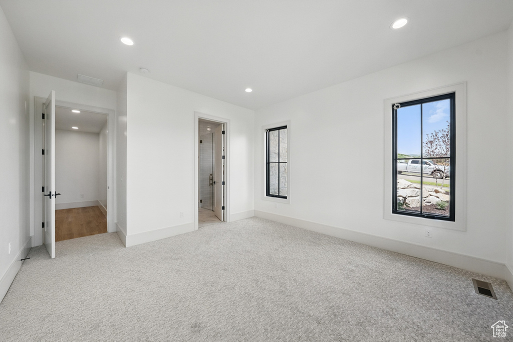 Unfurnished bedroom with light carpet, recessed lighting, and ensuite bathroom
