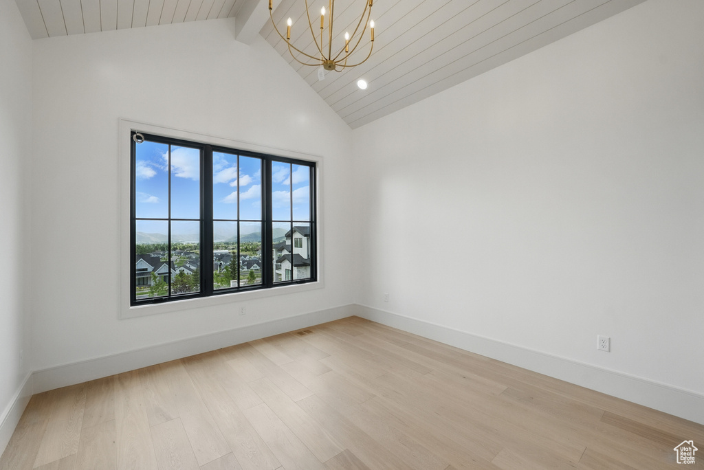 Unfurnished room with a chandelier, light wood-style flooring, high vaulted ceiling, beamed ceiling, and baseboards