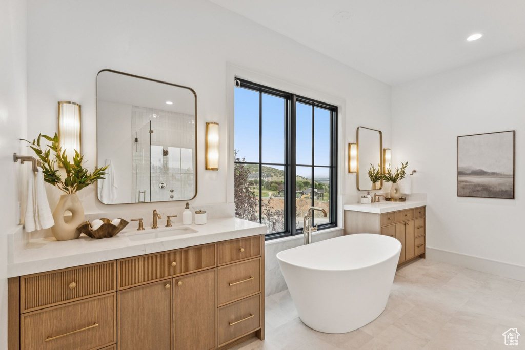 Bathroom featuring two vanities, a shower stall, a soaking tub, and recessed lighting