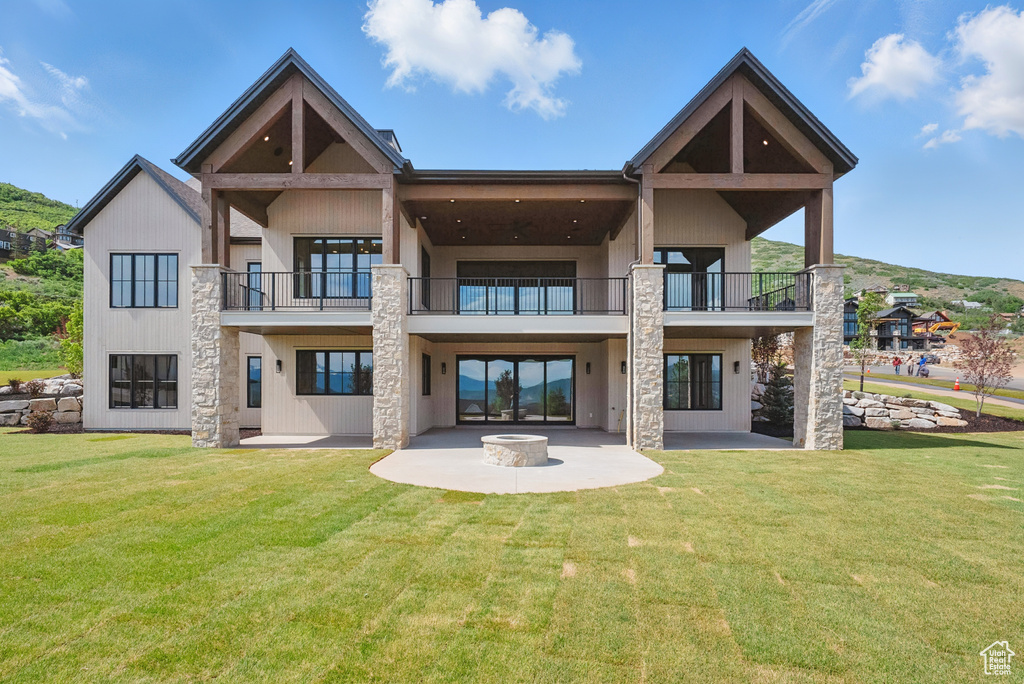 Back of property with a balcony, a patio area, and a yard