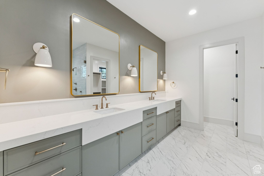Full bath featuring double vanity, marble look tiles, a shower, and recessed lighting